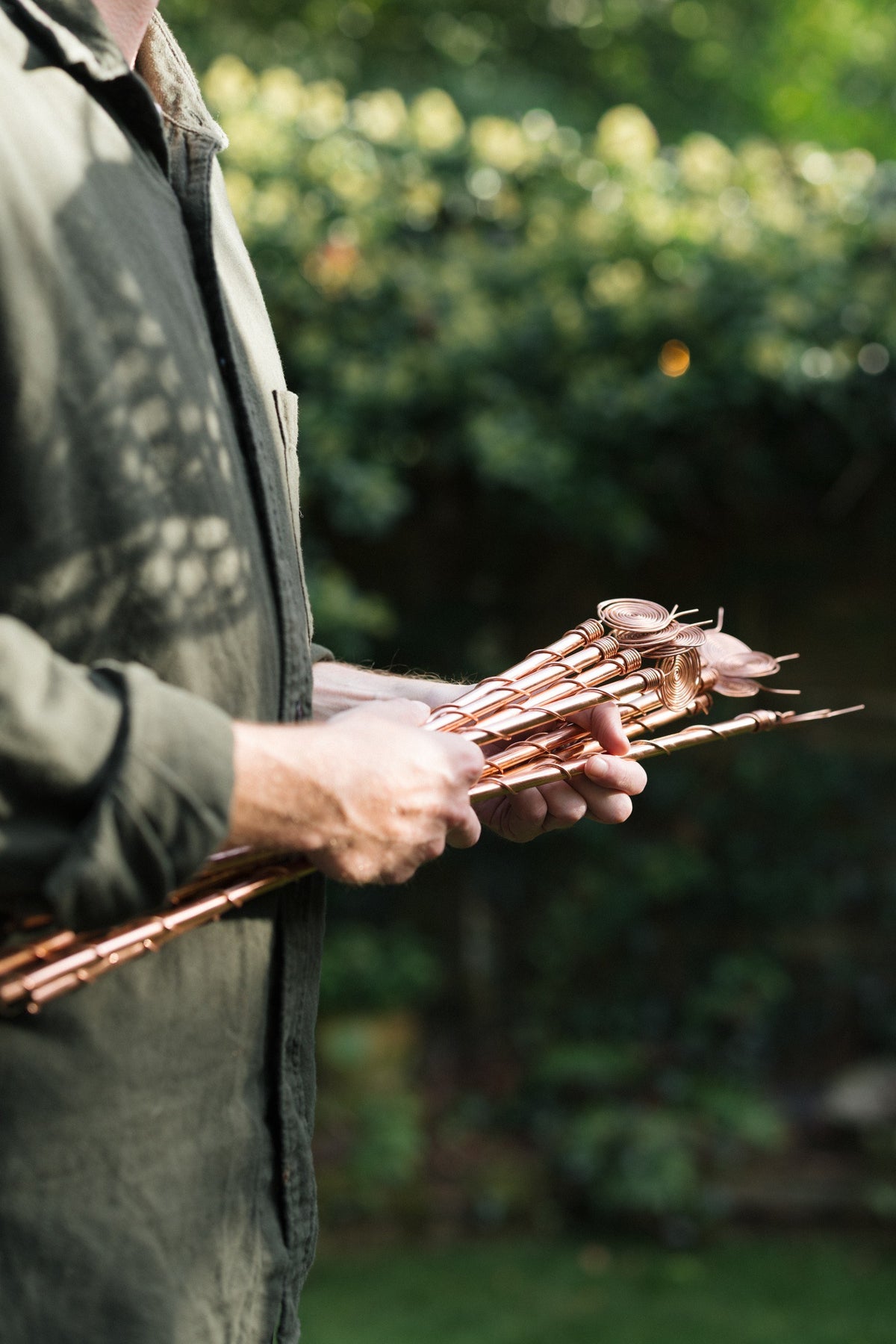 Kopero Elektrocultuur, een bos koperen antennes in twee handen in de tuin
