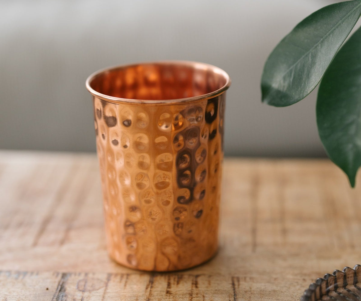 Kopero Koperen Beker Gehamerd, op een houten tafel voor een bank