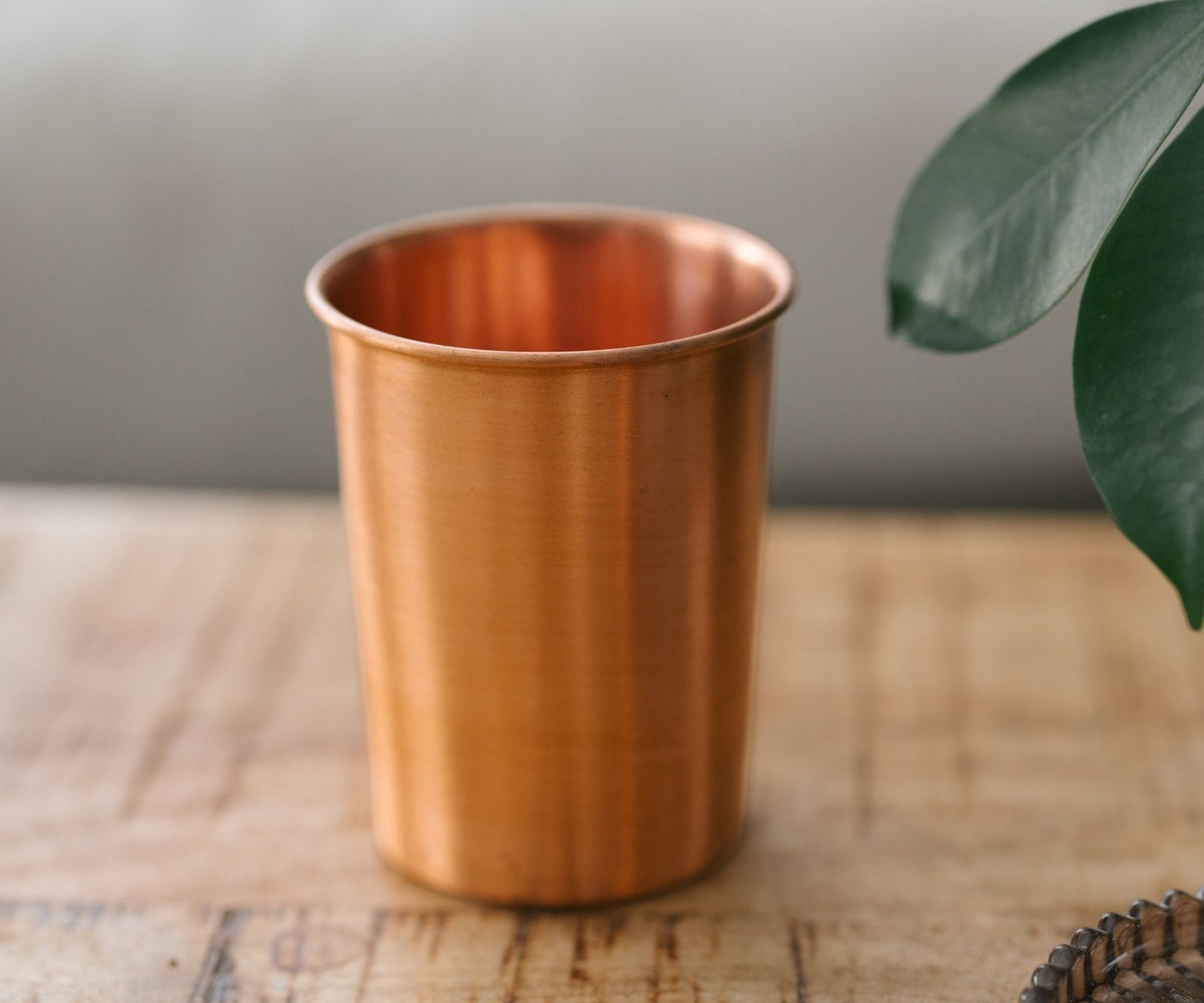 Kopero Koperen Beker Glad, op een houten tafel voor een bank