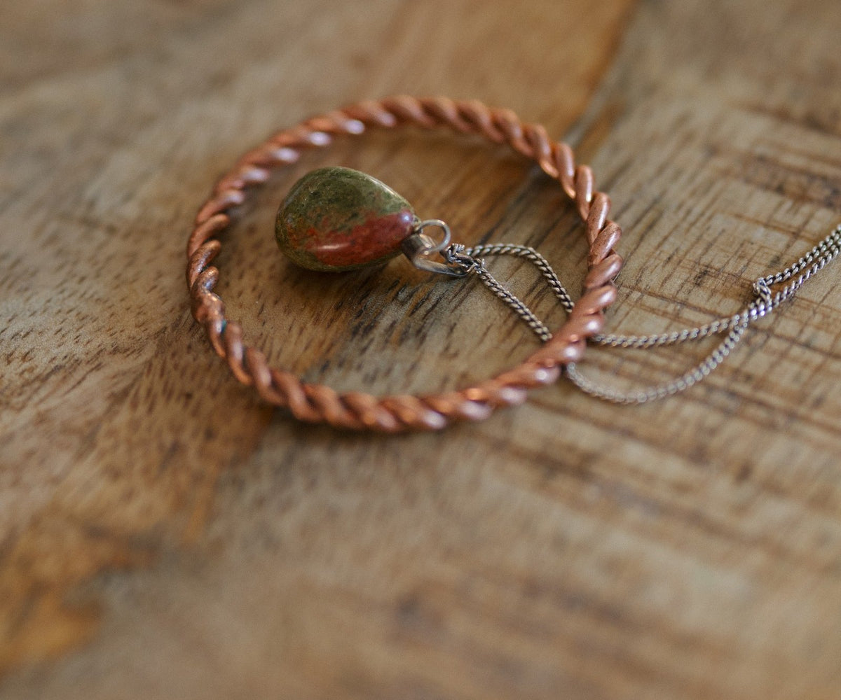 Kopero Koperen Tensorring, op een houten tafel met een hanger van unakiet