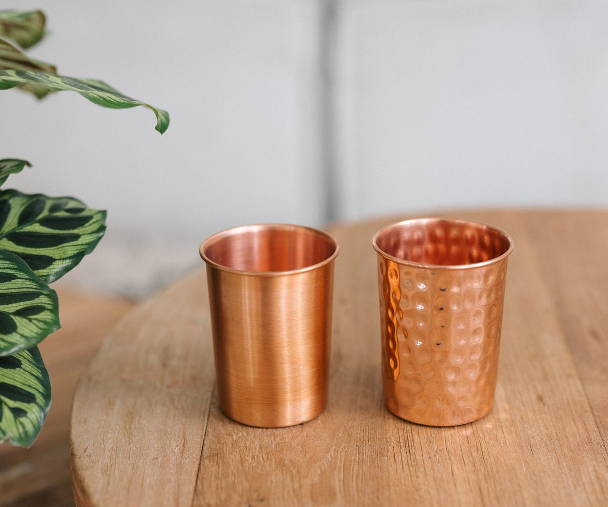 Kopero Koperen Beker, een gladde en een gehamerde beker naast elkaar op een ronde houten tafel