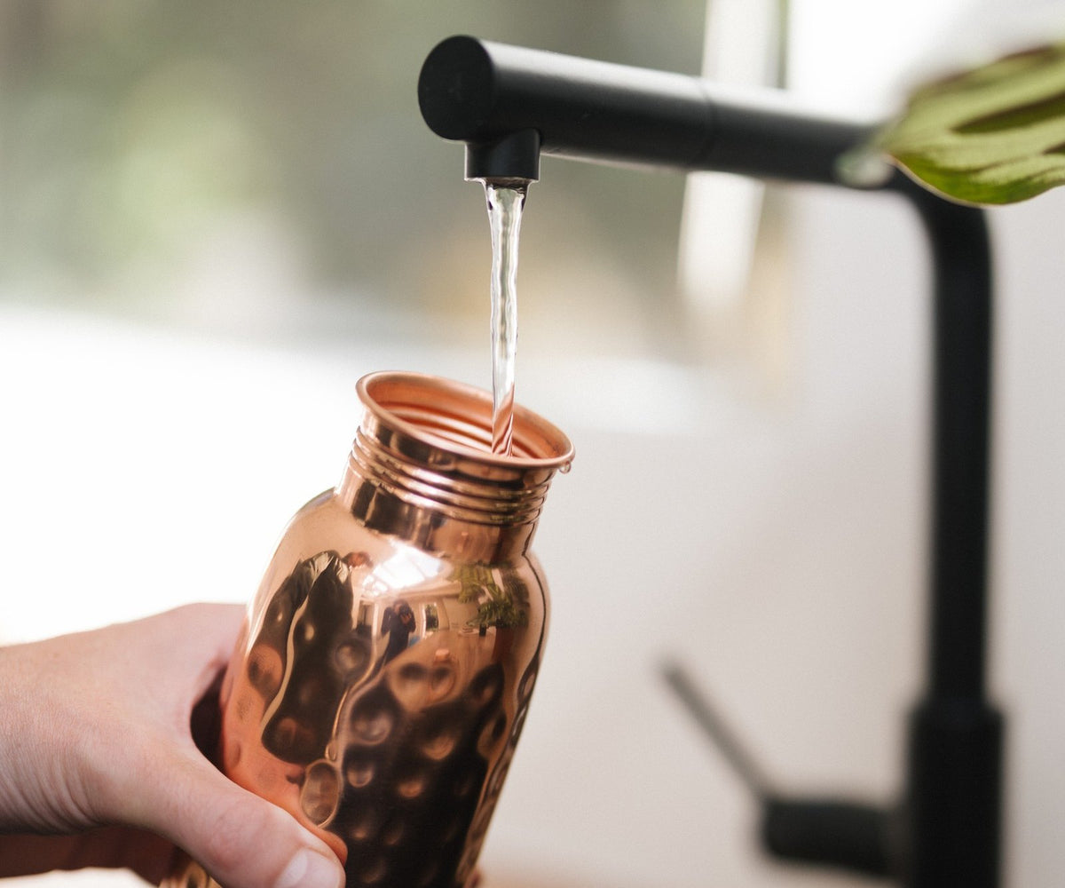 Kopero Koperen Waterfles Gehamerd, onder de kraan, terwijl er water in stroomt