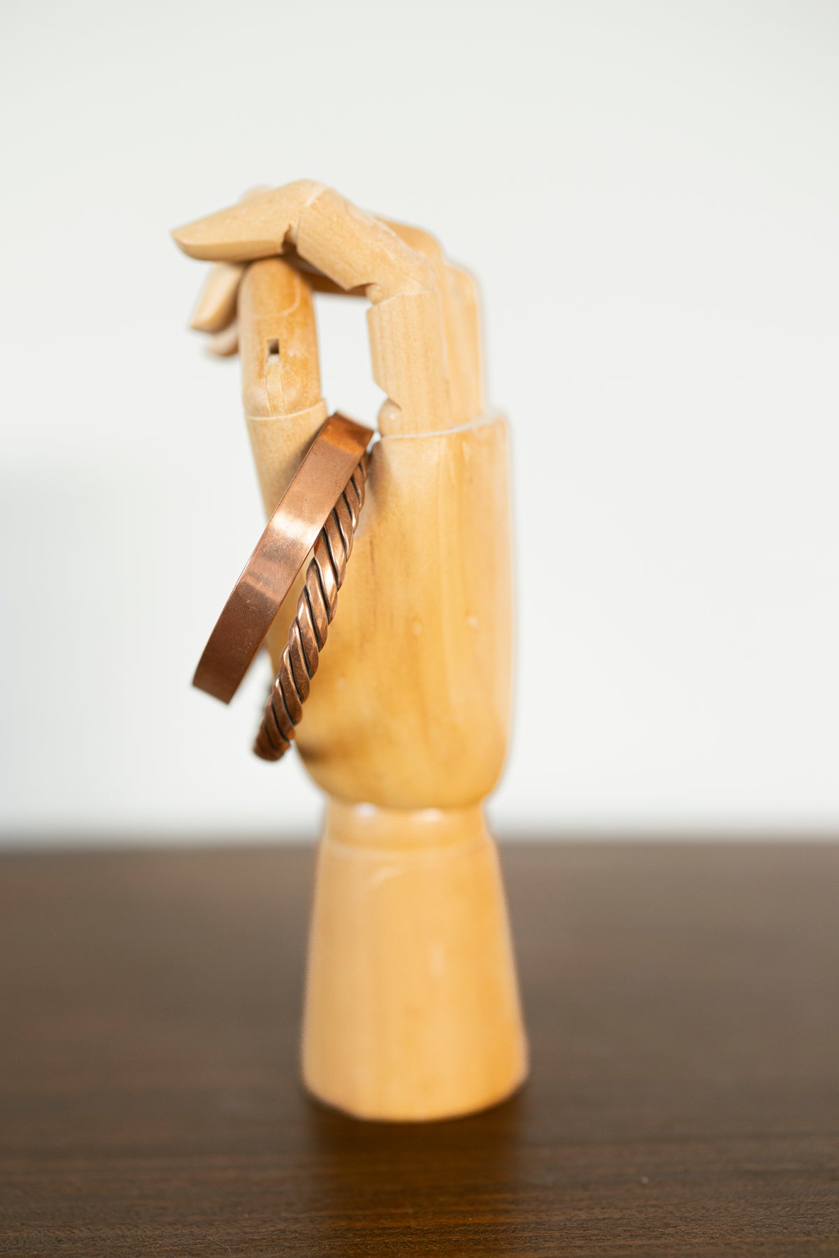 Kopero Premium Koperen Armbanden Gedraaid en Glad, zijaanzicht op houten sieradenhand