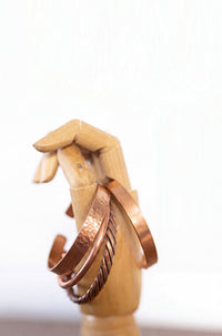 Kopero Koperen Armband, alle vier de uitvoeringen naast elkaar op een houten sieradenhand