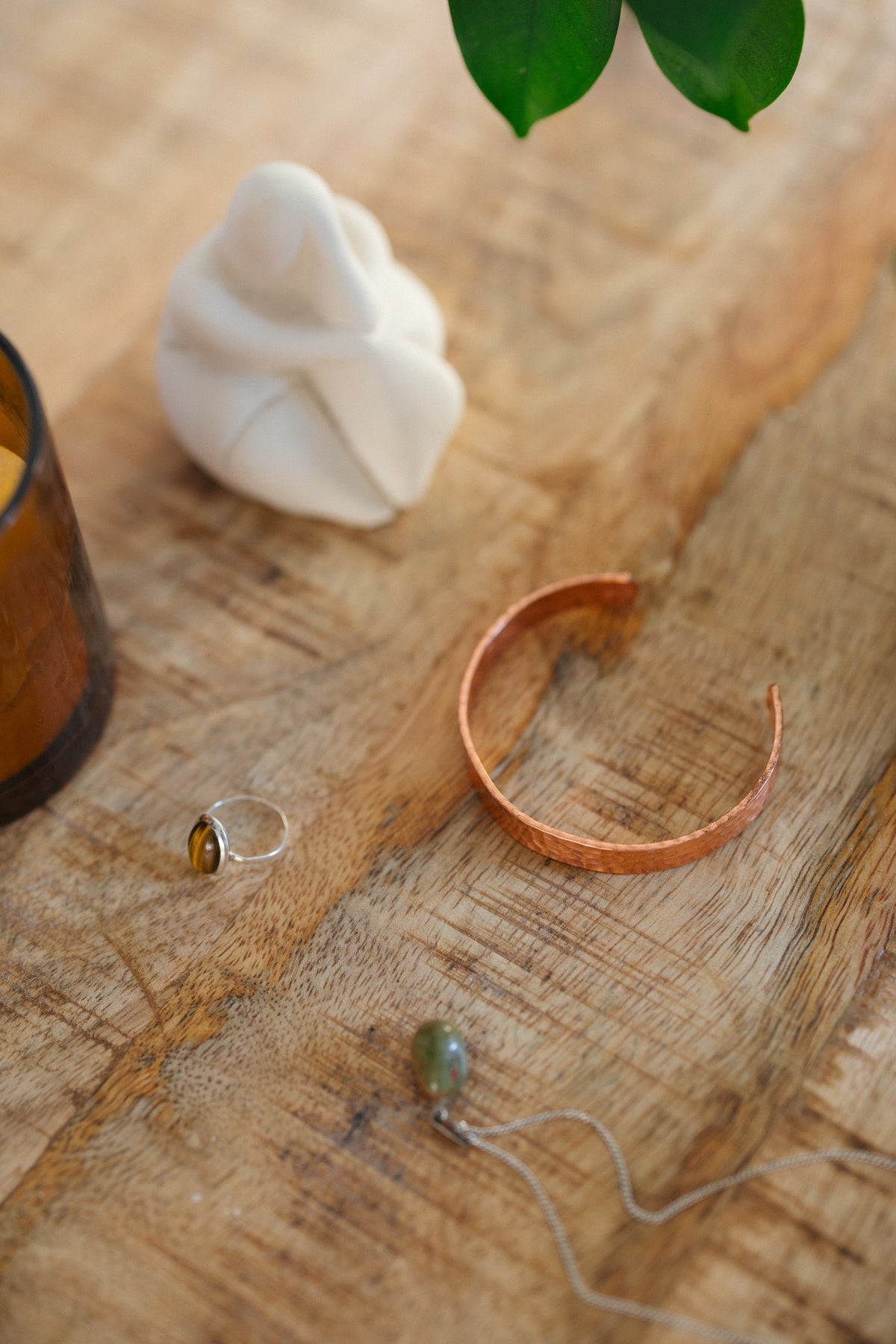 Kopero Koperen Armband Gehamerd, op een houten tafel naast een beeldje en een ring