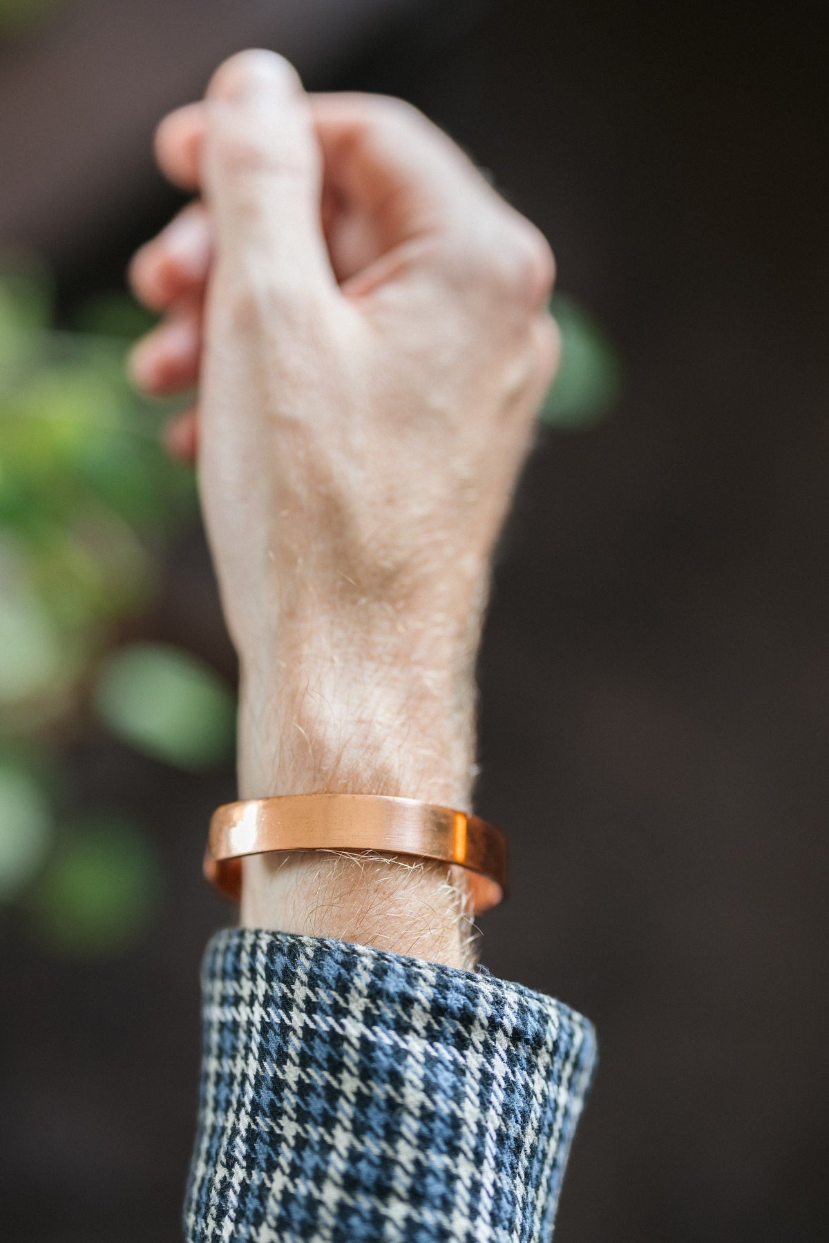 Kopero Koperen Armband Glad, om de pols, met de hand omhoog tegen een donkere achtergrond