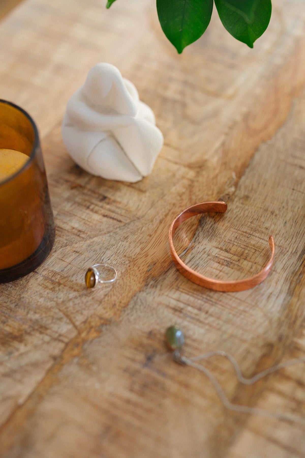 Kopero Koperen Armband Glad, op een houten tafel naast een beeldje en een ring