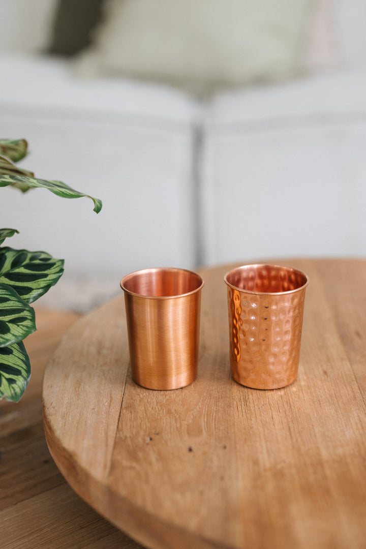 Kopero Koperen Beker, een gladde en een gehamerde beker naast elkaar op een ronde houten tafel