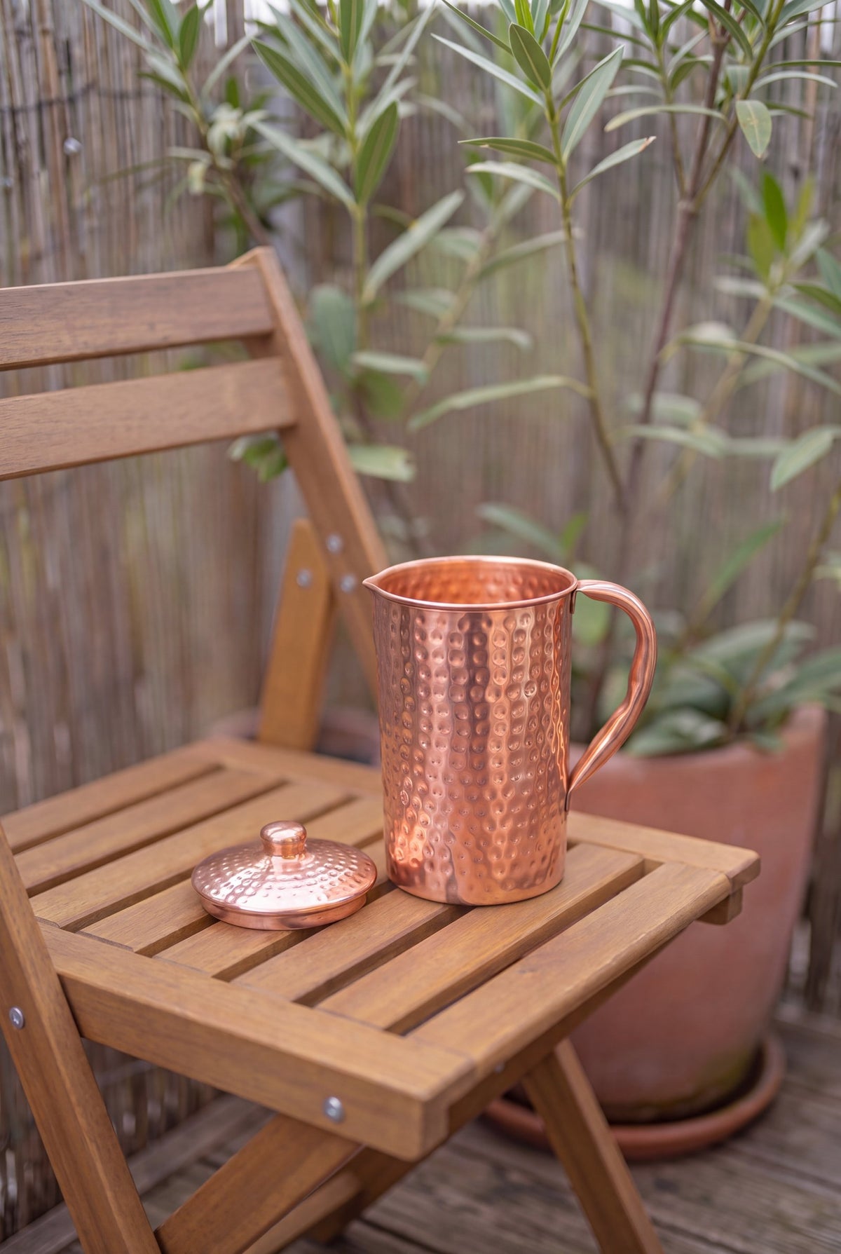 Kopero Koperen Kan Gehamerd buiten op een houten tuinstoel, met het deksel ernaast