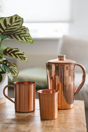 Kopero Koperen Kan Glad, met een mok en een beker op een houten tafel