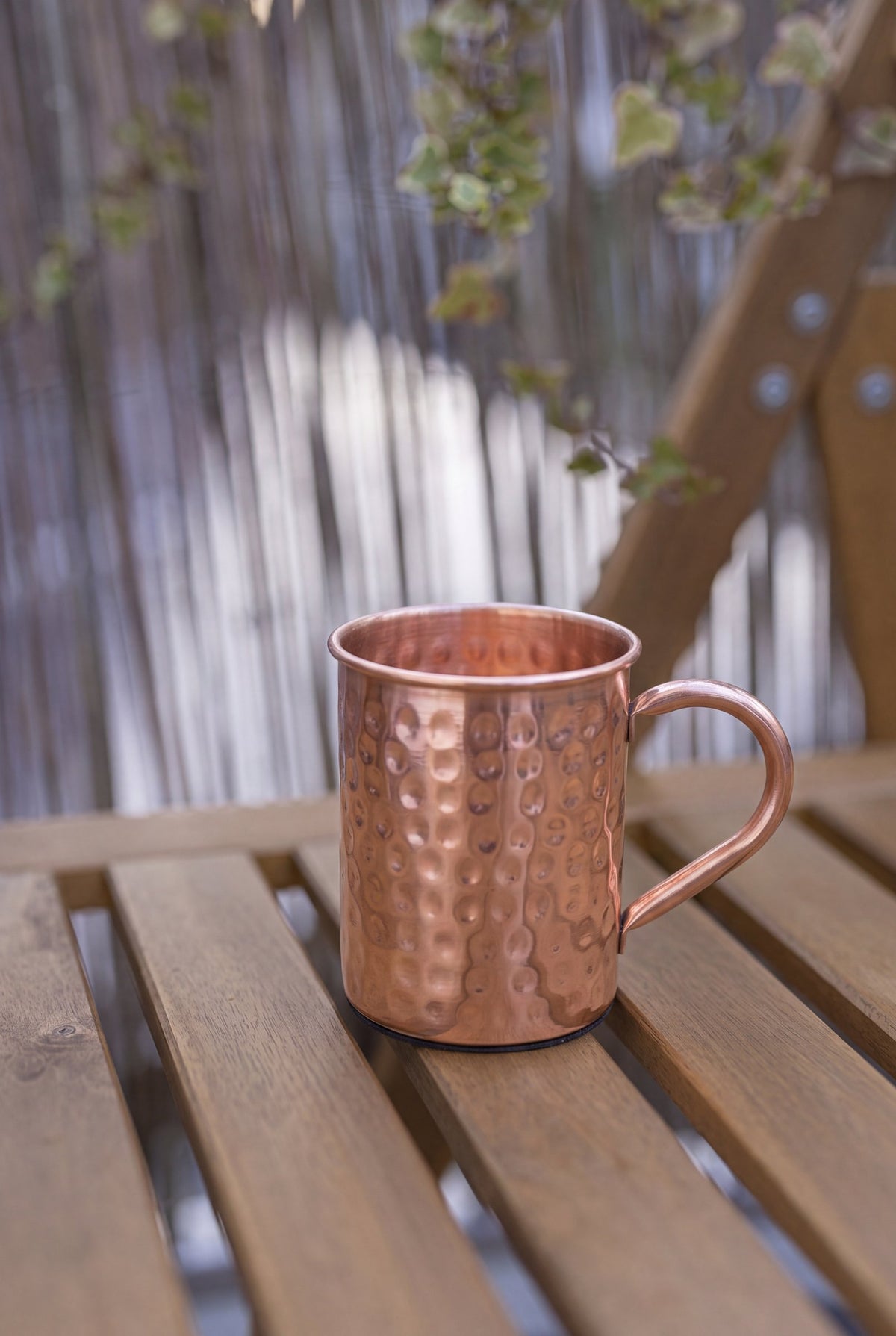 Kopero Koperen Mok Gehamerd van 400 ml op een houten tuinbank