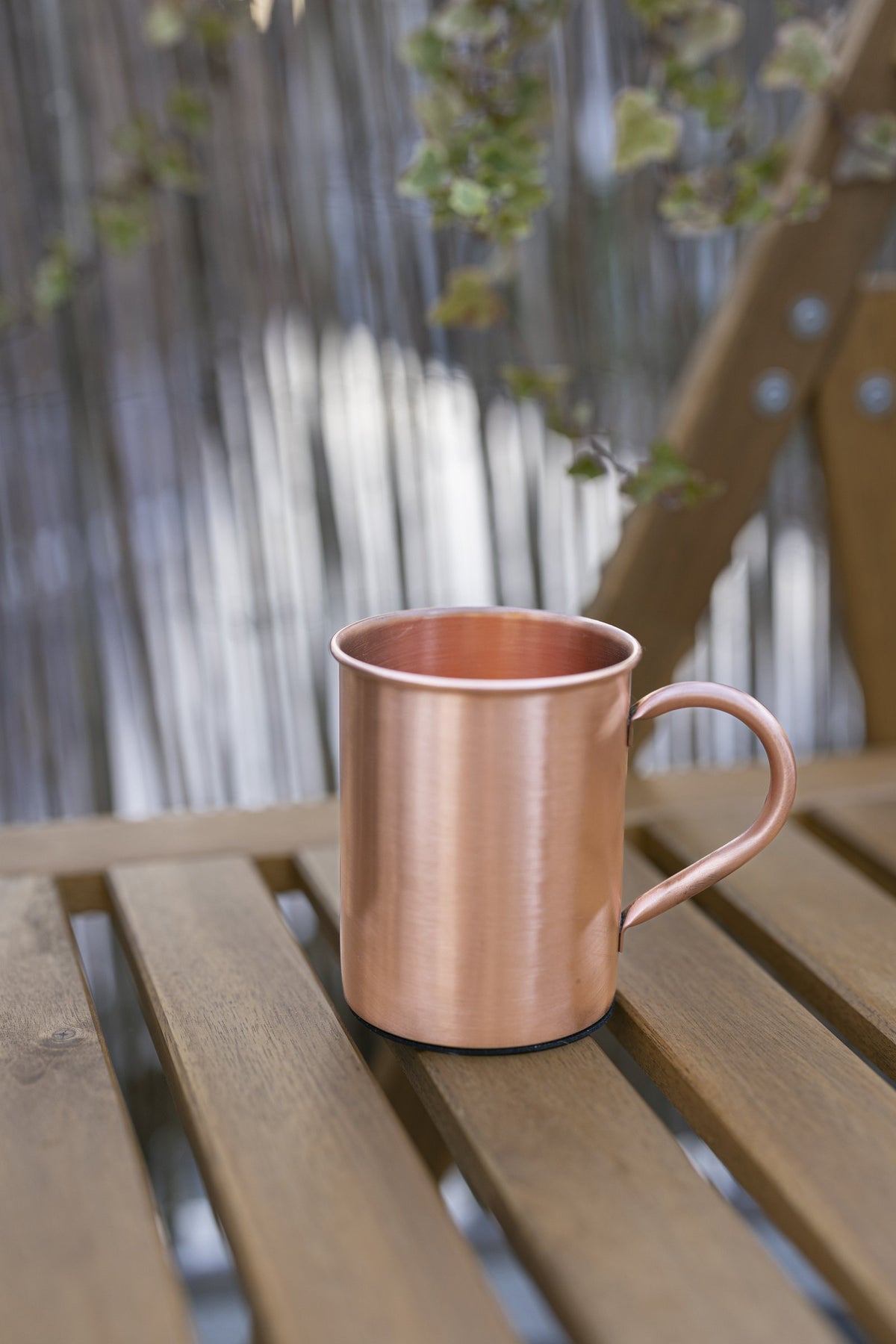 Kopero Koperen Mok Glad van 400 ml op een houten tuinbank