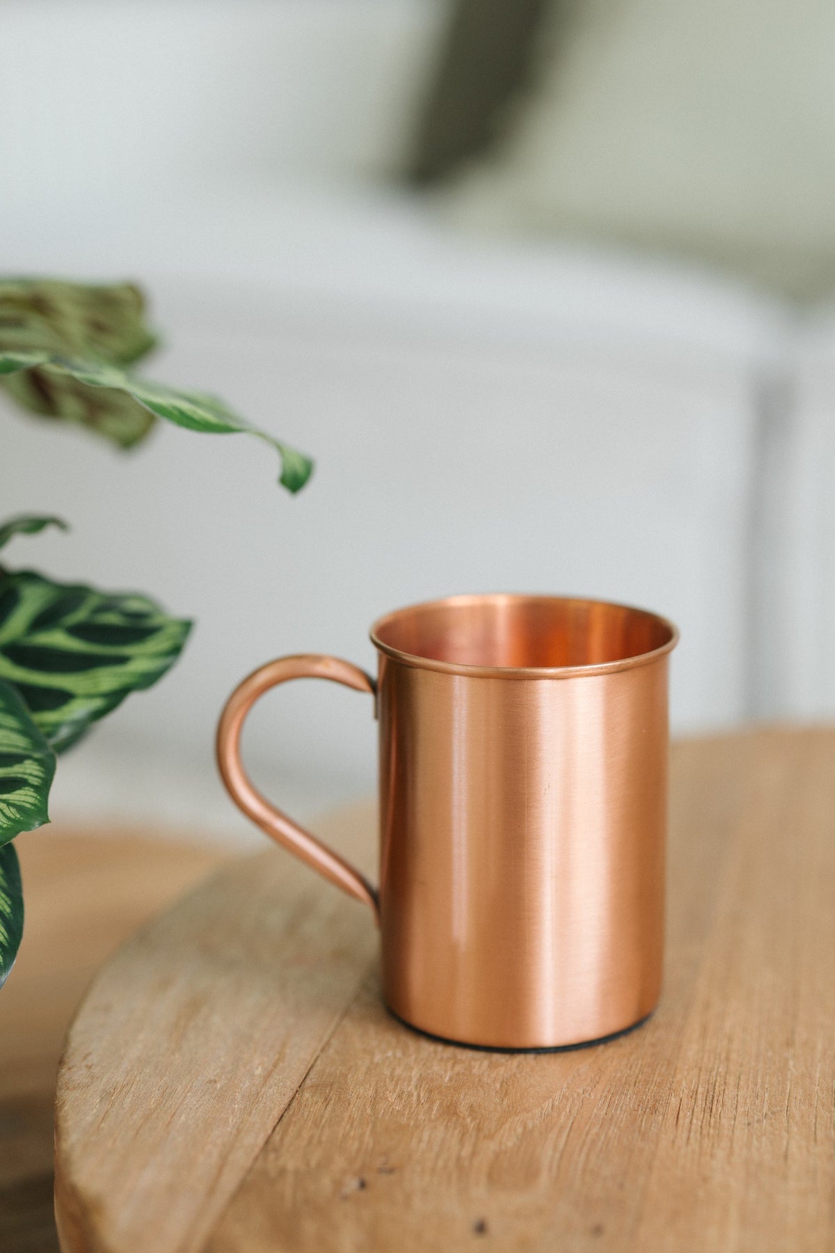 Kopero Koperen Mok Glad, op een ronde houten tafel voor een bank