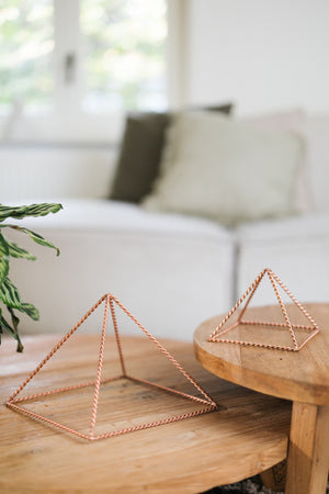 Kopero Koperen Piramide Energizer Gedraaid, de kleine en de grote piramide naast elkaar op twee houten tafels