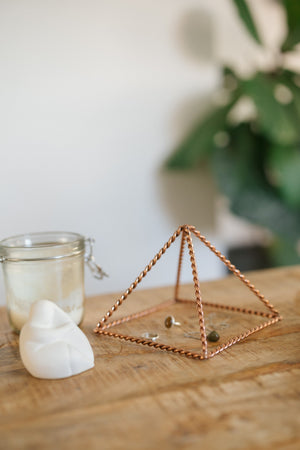 Kopero Koperen Piramide Energizer Gedraaid Klein (14,56 cm), met sieraden eronder naast een kaarsenpot en een beeldje