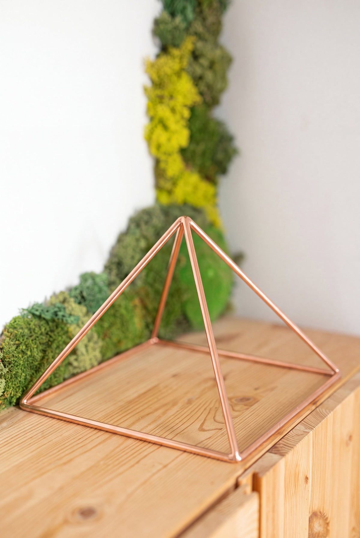 Kopero Koperen Piramide Energizer Glad Groot (23,56 cm) op een grenen kast voor een mosschilderij