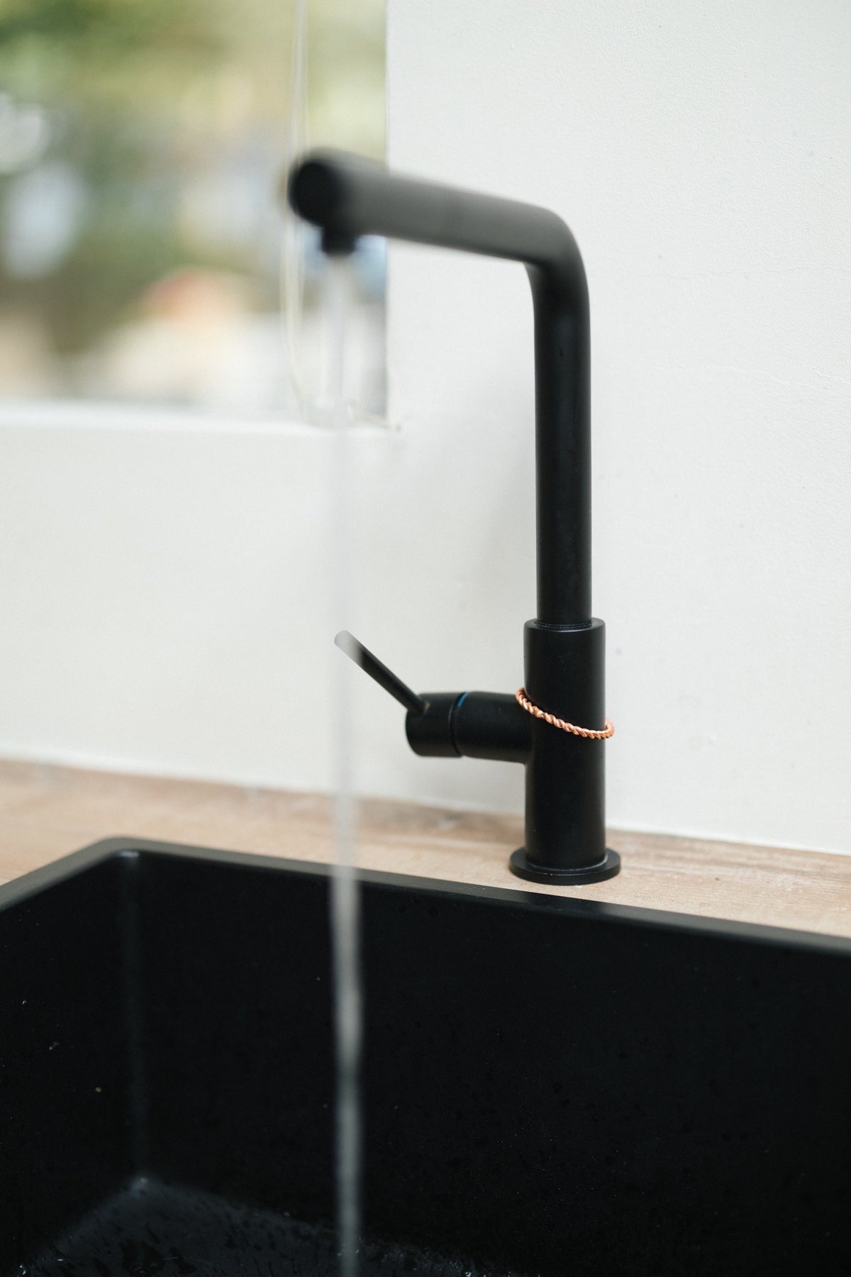 Kopero Koperen Tensorring, om de kraan van een zwarte keukenkraan met stromend water