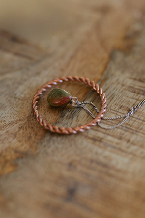 Kopero Koperen Tensorring, op een houten tafel met een hanger van unakiet