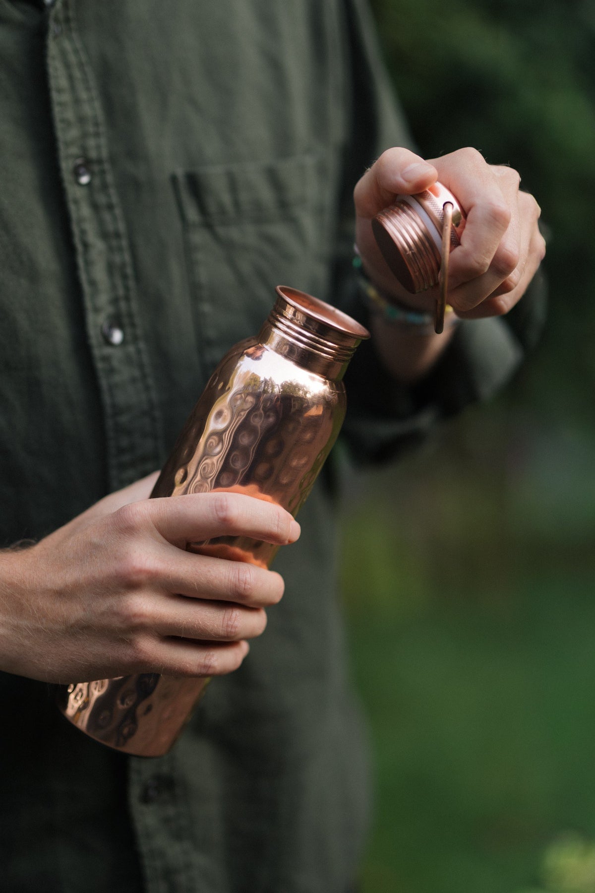 Kopero Koperen Waterfles Gehamerd, in een hand, terwijl de dop wordt losgedraaid